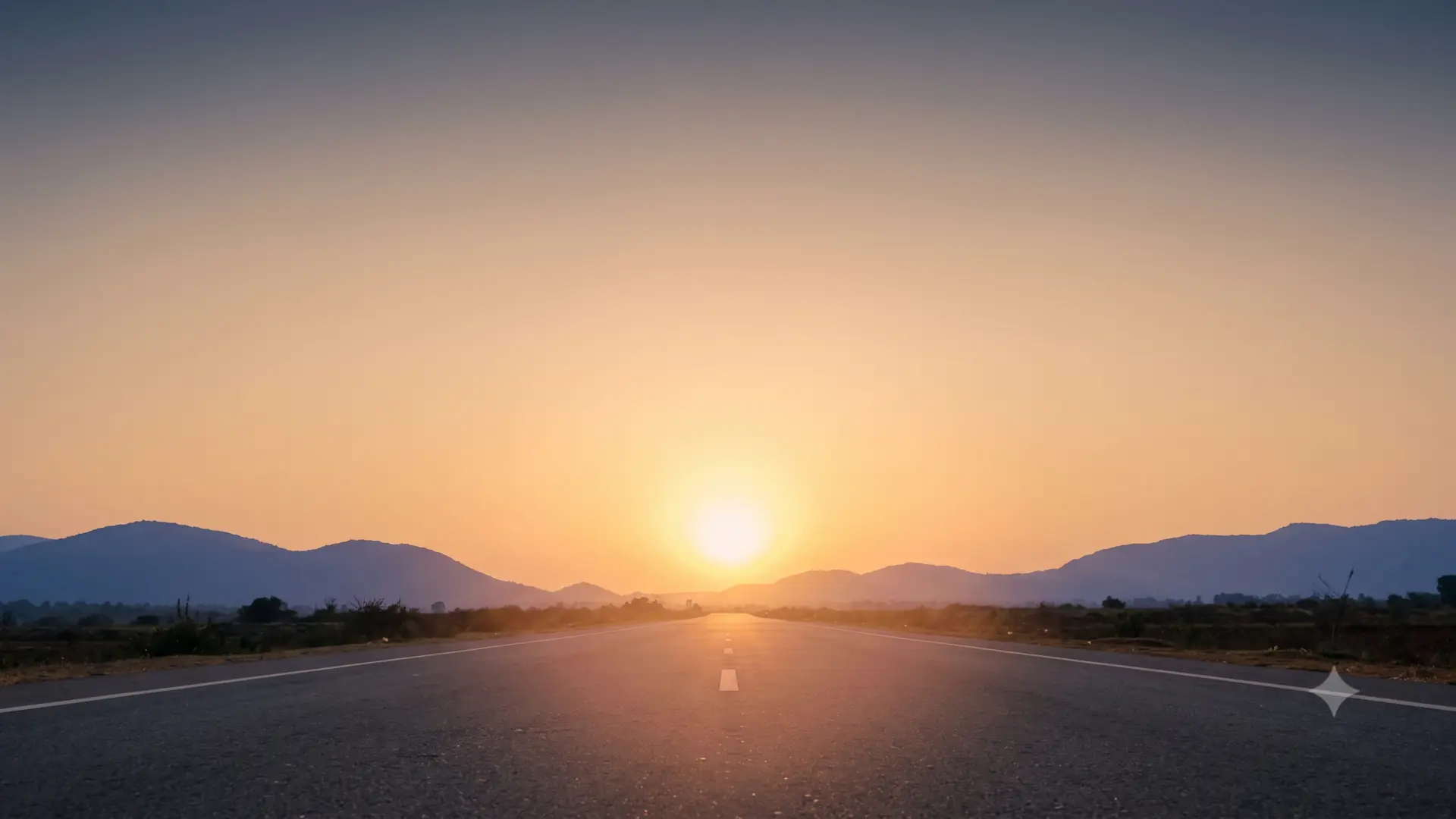 A long open road stretching toward a warm setting sun between low silhouetted hills