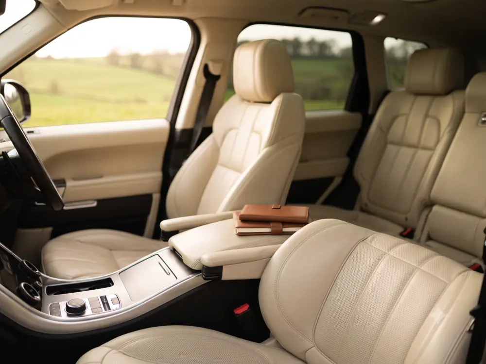 Interior view of a premium vehicle cabin with cream leather upholstery and soft ambient light